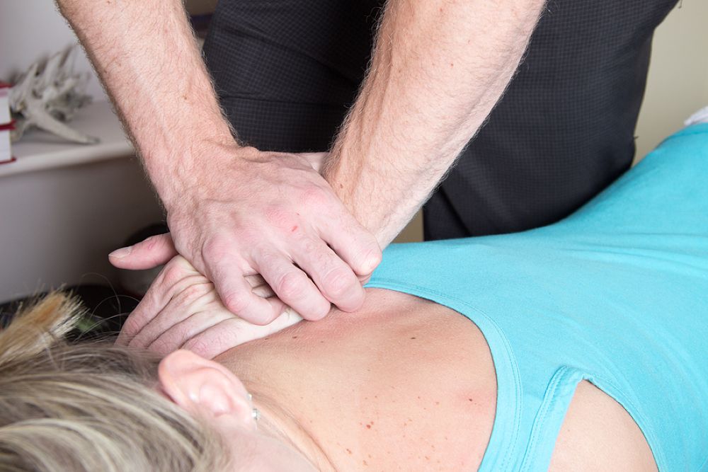 Chiropractor's hands exerting pressure on patient's upper back