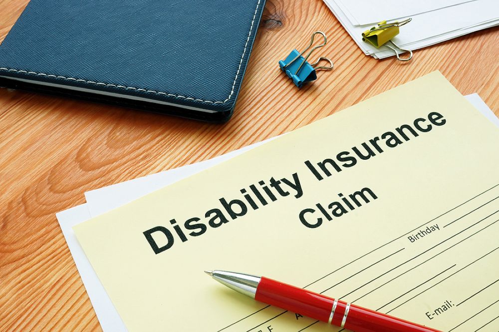 Disability Claim Form yellow paper form on a desk with a pen and notepad