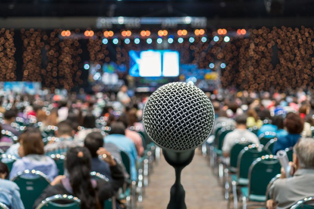 Perspective from behind a microphone speaking in front of a large audience