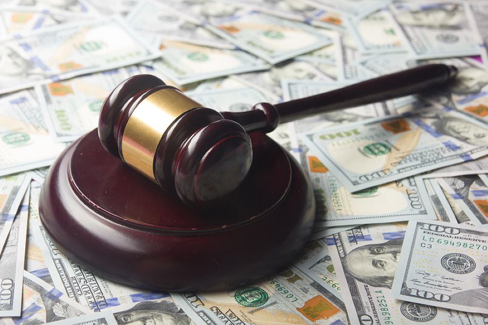 Wooden judges gavel on top of table covered with American $100 bills