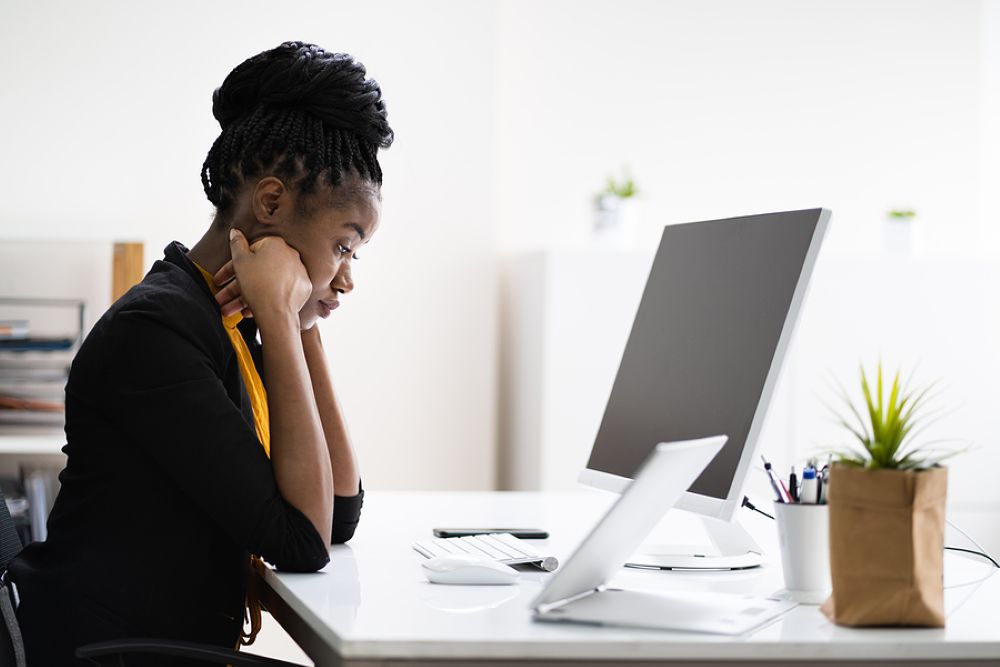 Professional black woman worried in front of a desktop computer