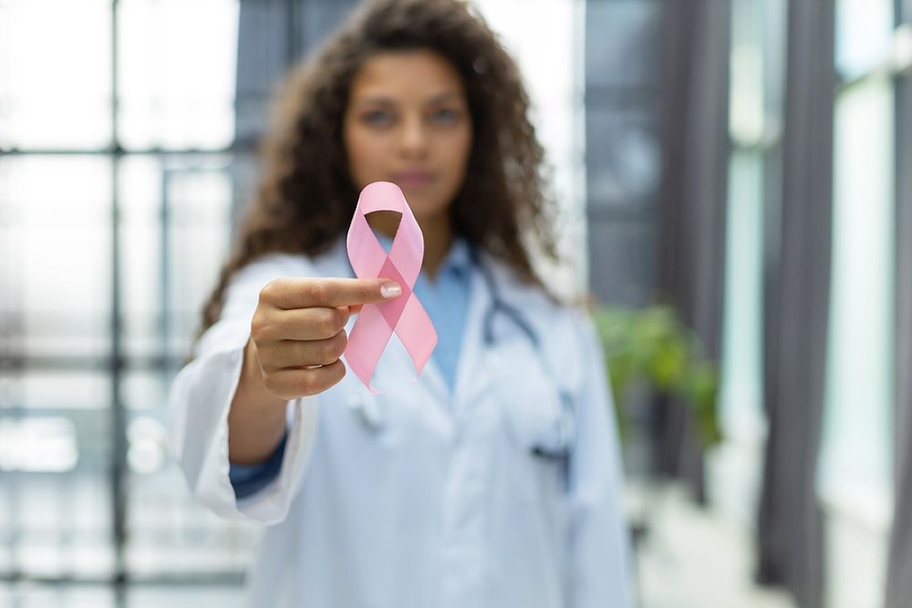 Female doctor holding pink ribbon representing breast cancer awareness