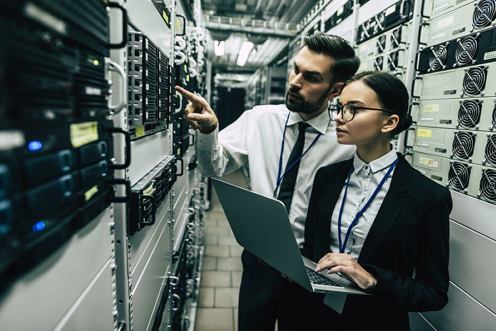 Tech professionals in data center checking on server racks